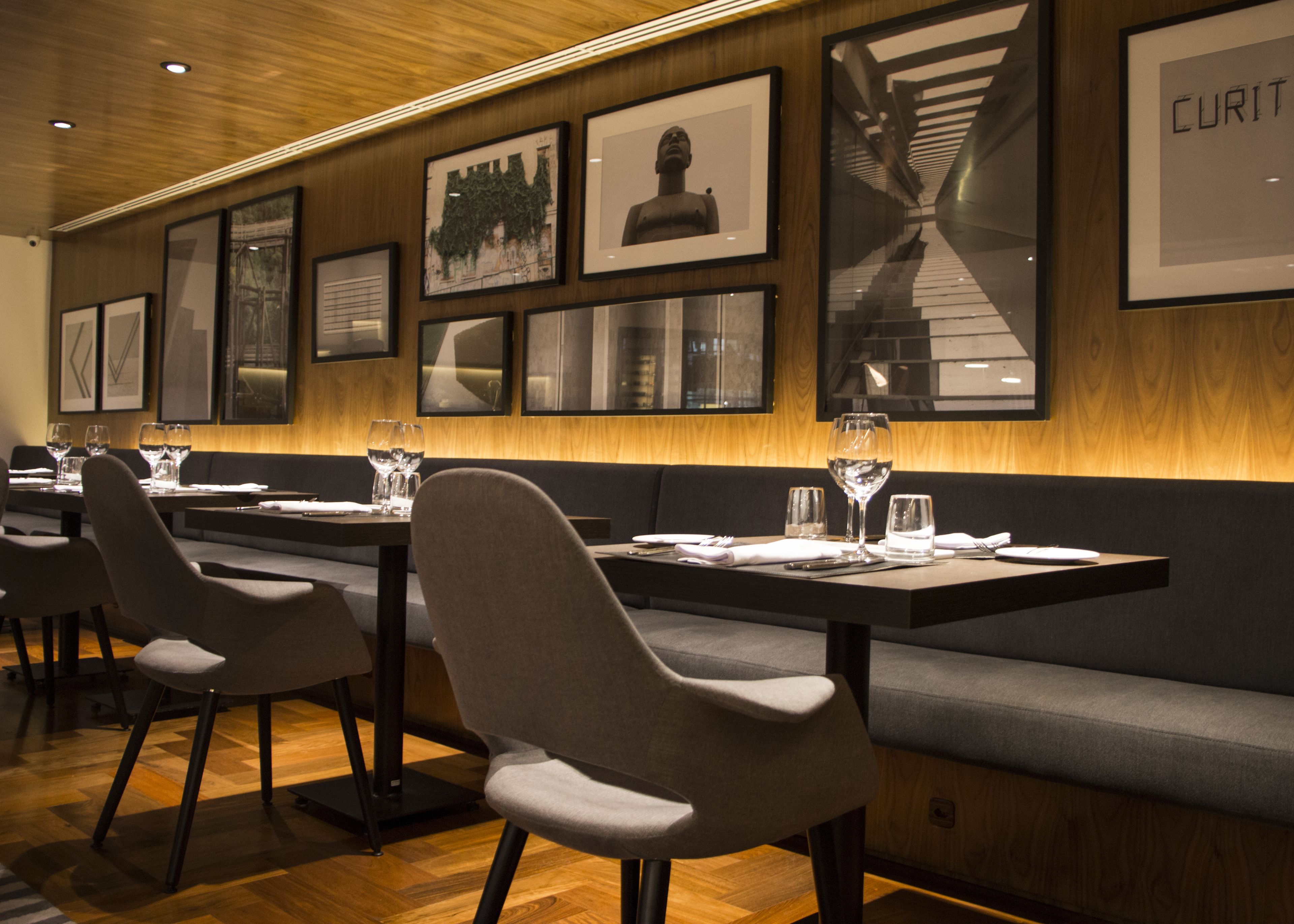 En restaurantindretning med træpaneler, billeder i rammer på væggene og moderne siddepladser.