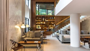 Una sala moderna con una amplia estantería, dos sofás y una escalera.
