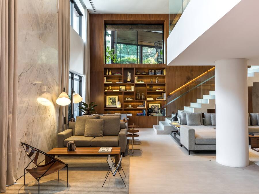 Una sala moderna con una amplia estantería, dos sofás y una escalera.