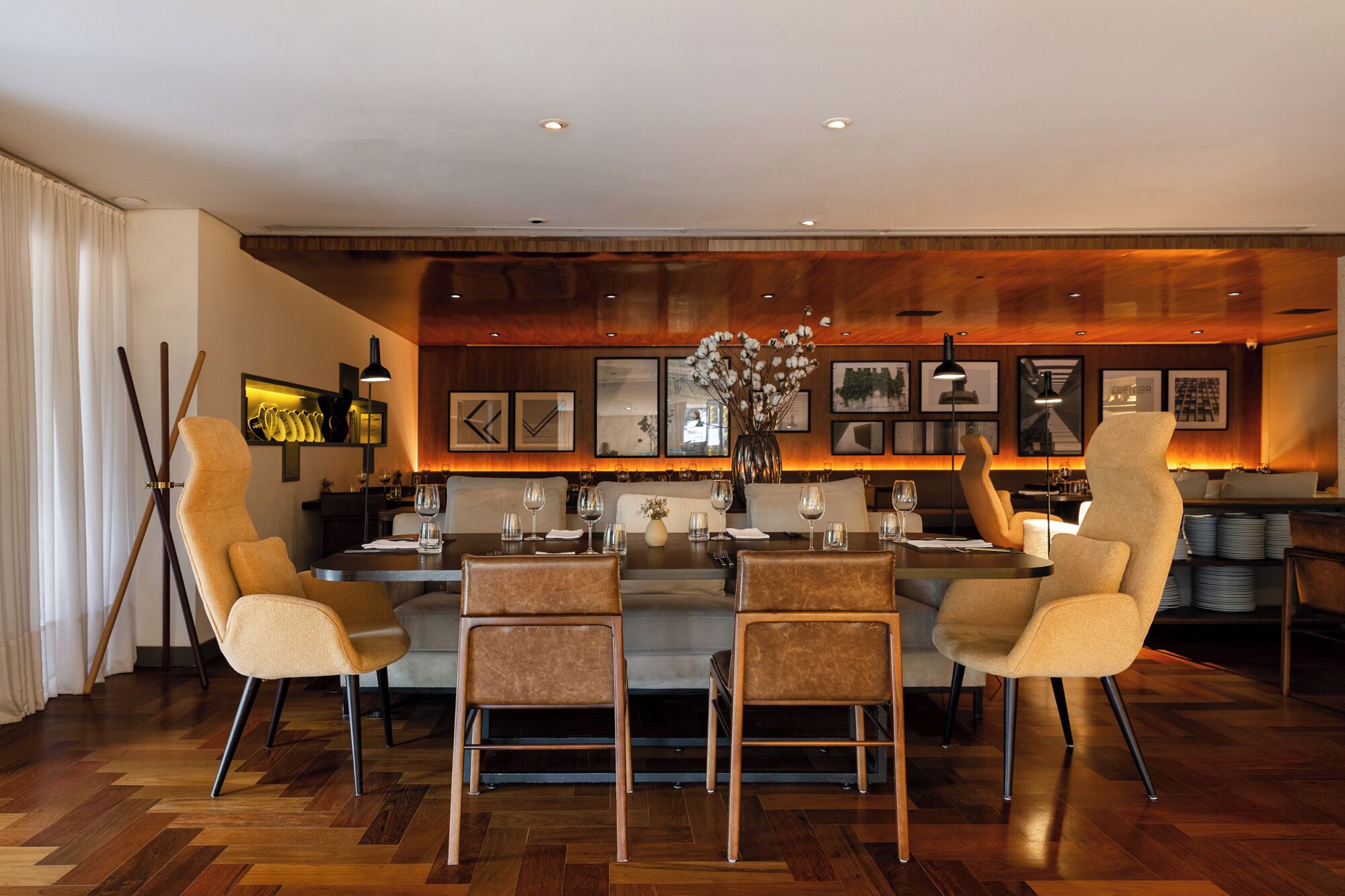 A modern dining area with a central island, high-backed chairs, and a wooden floor.