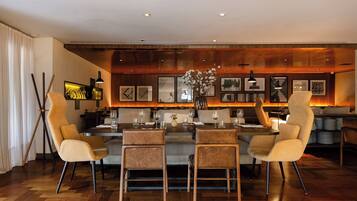 A modern dining area with a central island, high-backed chairs, and a wooden floor.