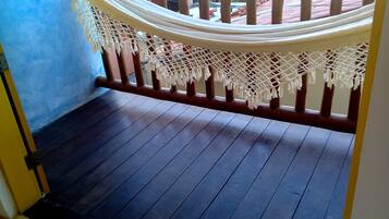 Une terrasse en bois avec un hamac et un auvent blanc en forme de moustiquaire.