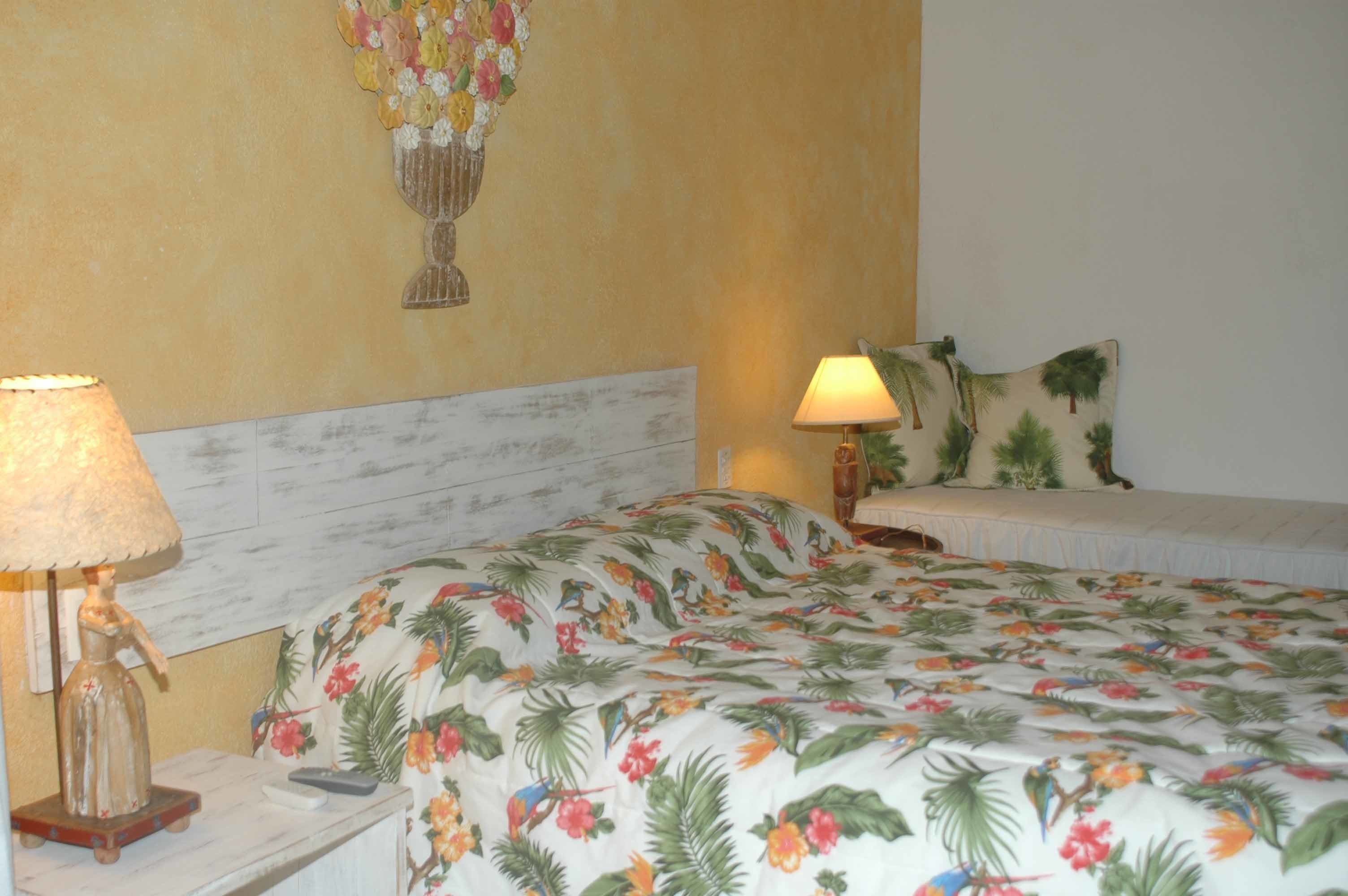 A hotel room with a bed, two bedside lamps, a nightstand, a floral wall decoration, and a white headboard.