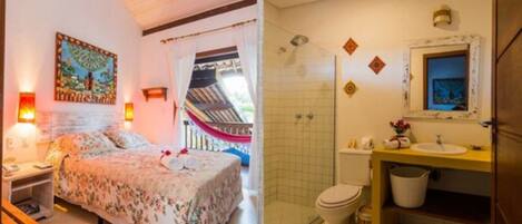 A bedroom with a bed, bedside table, and a painting on the wall. The bathroom includes a toilet, sink, and shower area.