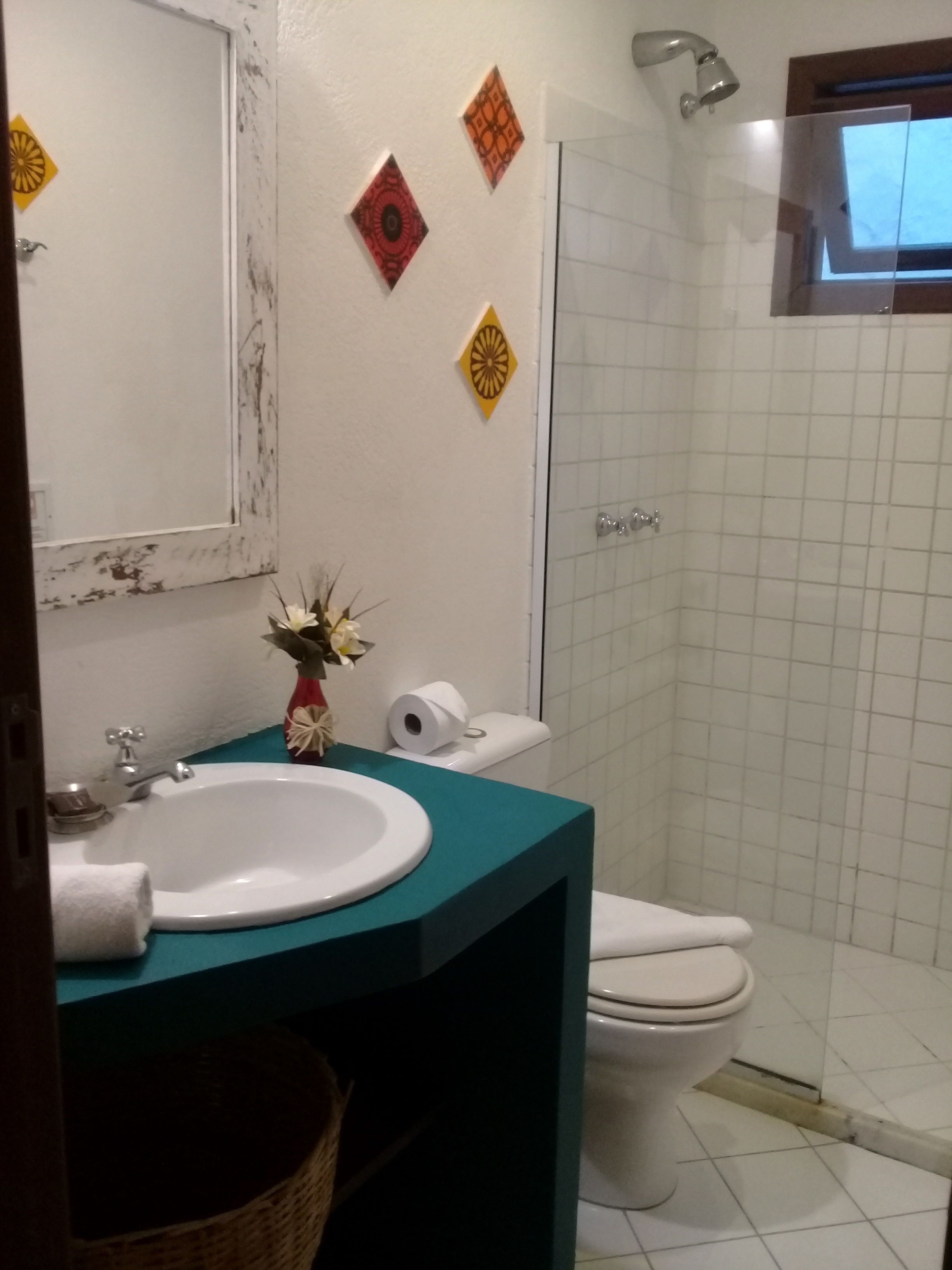 A bathroom with a white sink, a toilet, and a shower. There are decorative wall tiles and a mirror above the sink.