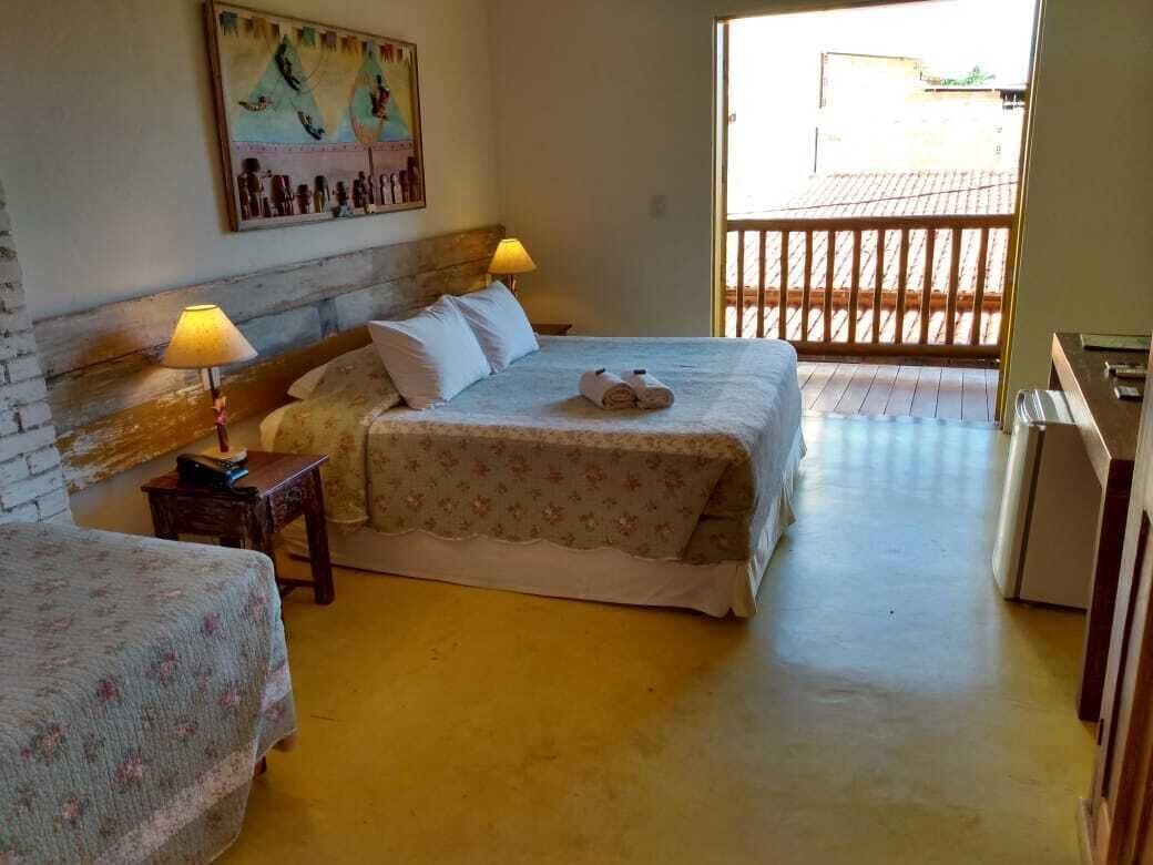 Une chambre avec deux lits, une tête de lit en bois, un tableau au mur et un balcon avec une balustrade.