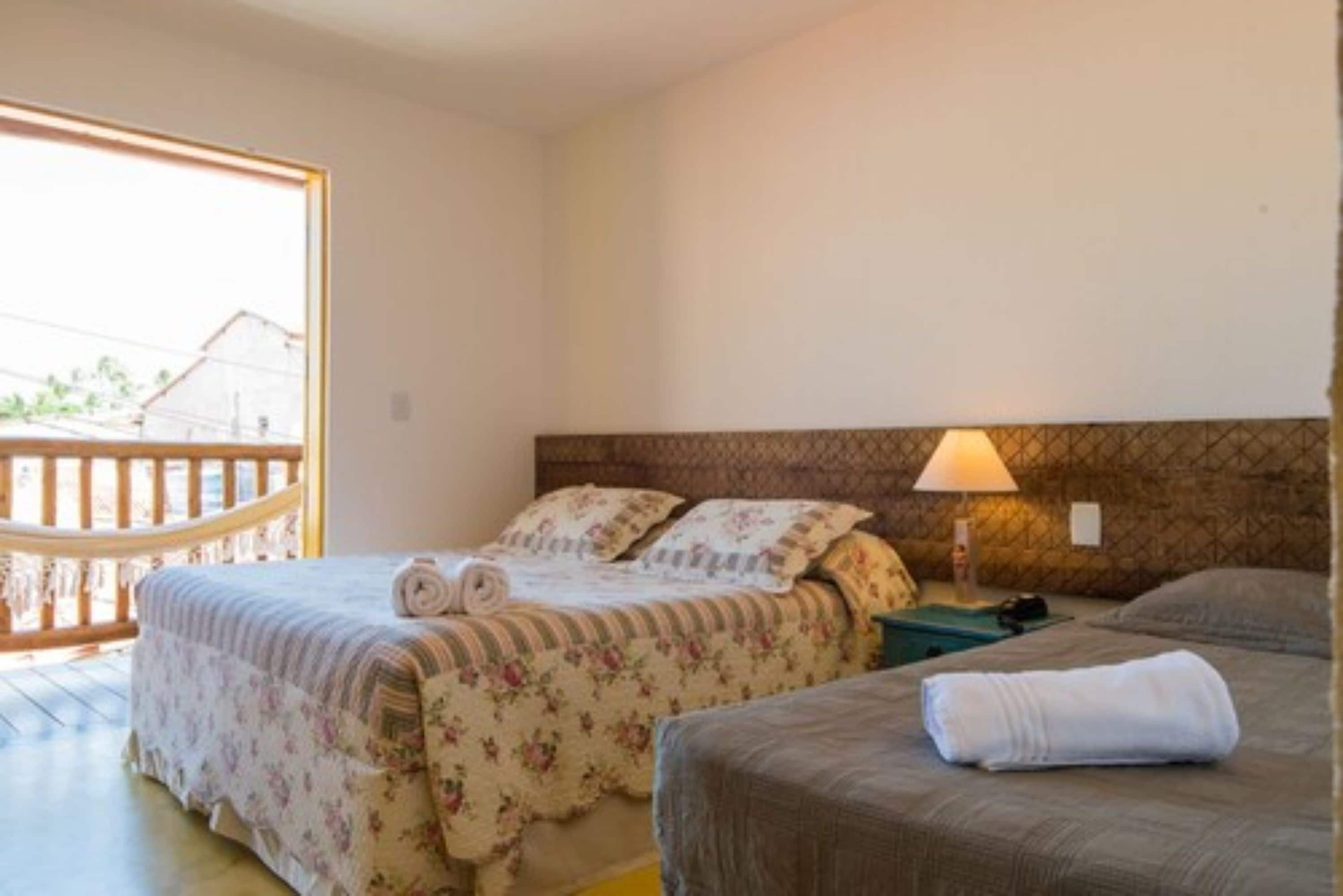 Una camera da letto con due letti, un balcone in legno e una lampada sul comodino.