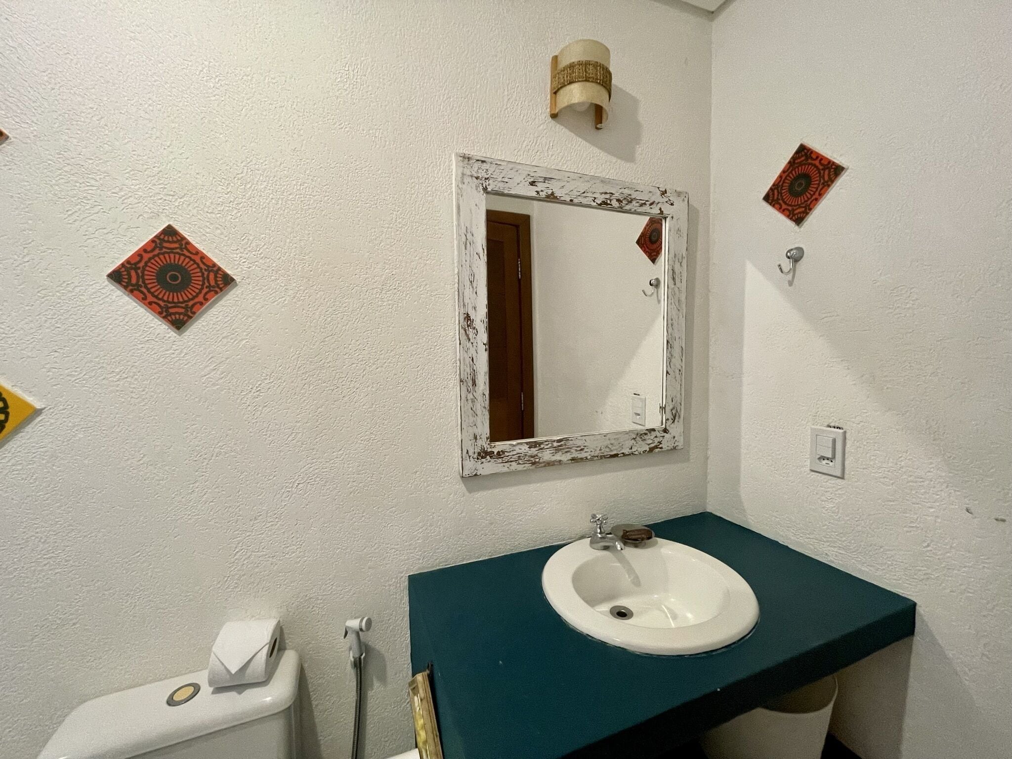 A bathroom with a white sink, a mirror, a towel dispenser, and a toilet.
