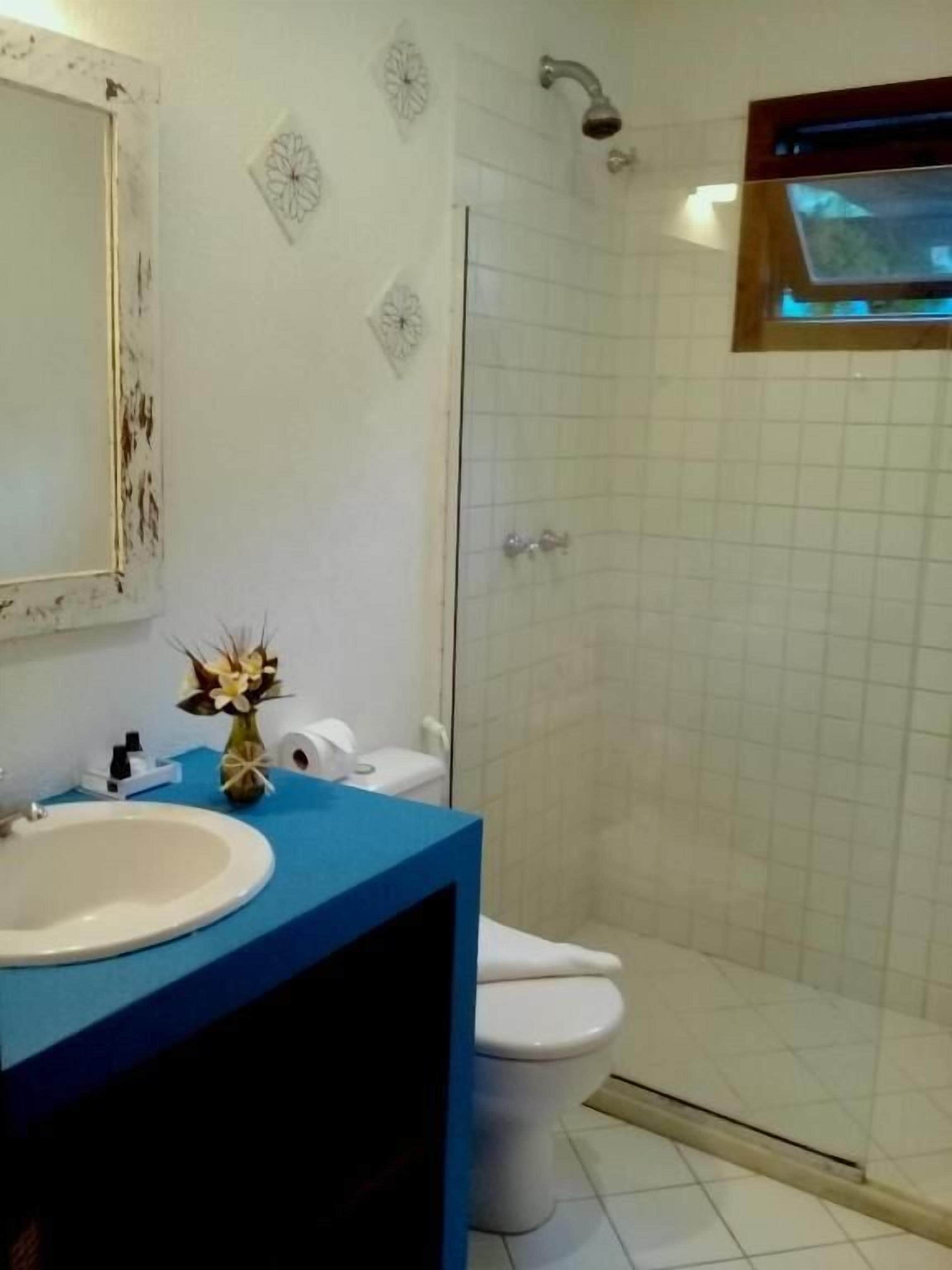 A bathroom with a white sink, blue countertop, and a shower enclosure.