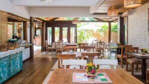 Un restaurant avec des tables et des chaises en bois, un ventilateur au plafond et un mur en briques.
