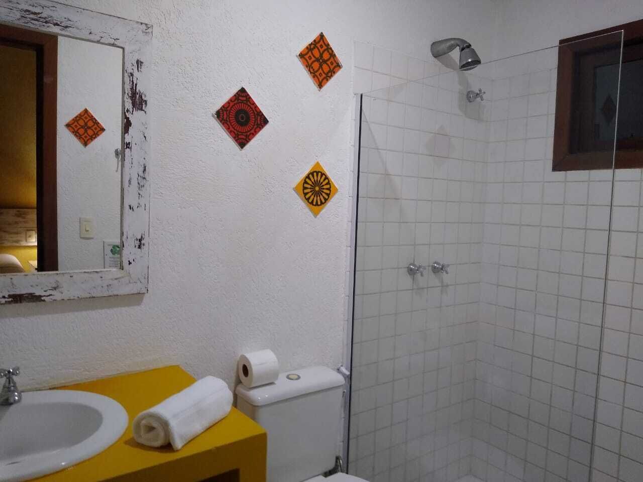 A bathroom with a yellow vanity, white sink, and a glass shower enclosure.