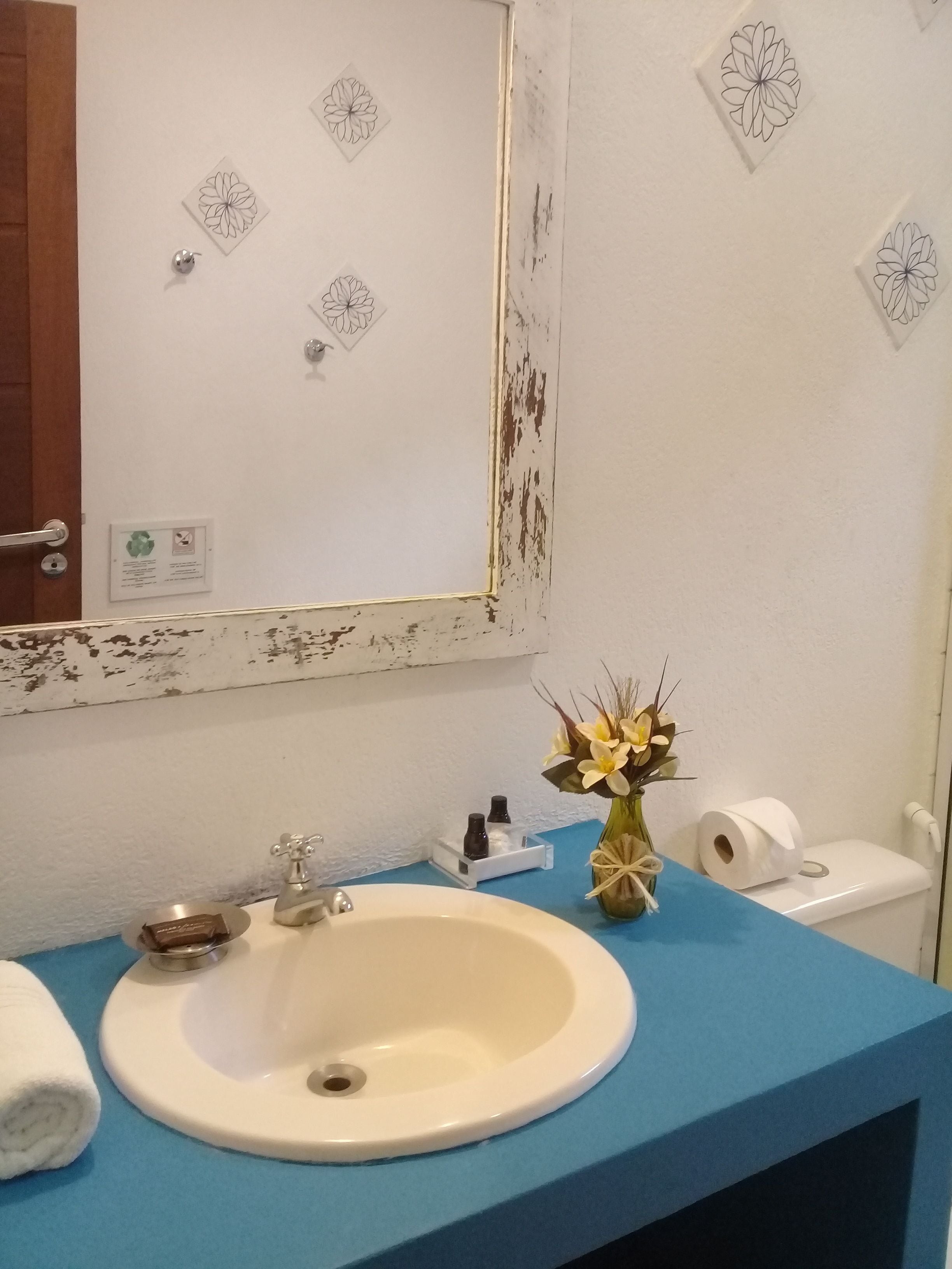 A bathroom with a white sink, blue countertop, and a mirror with floral decals.