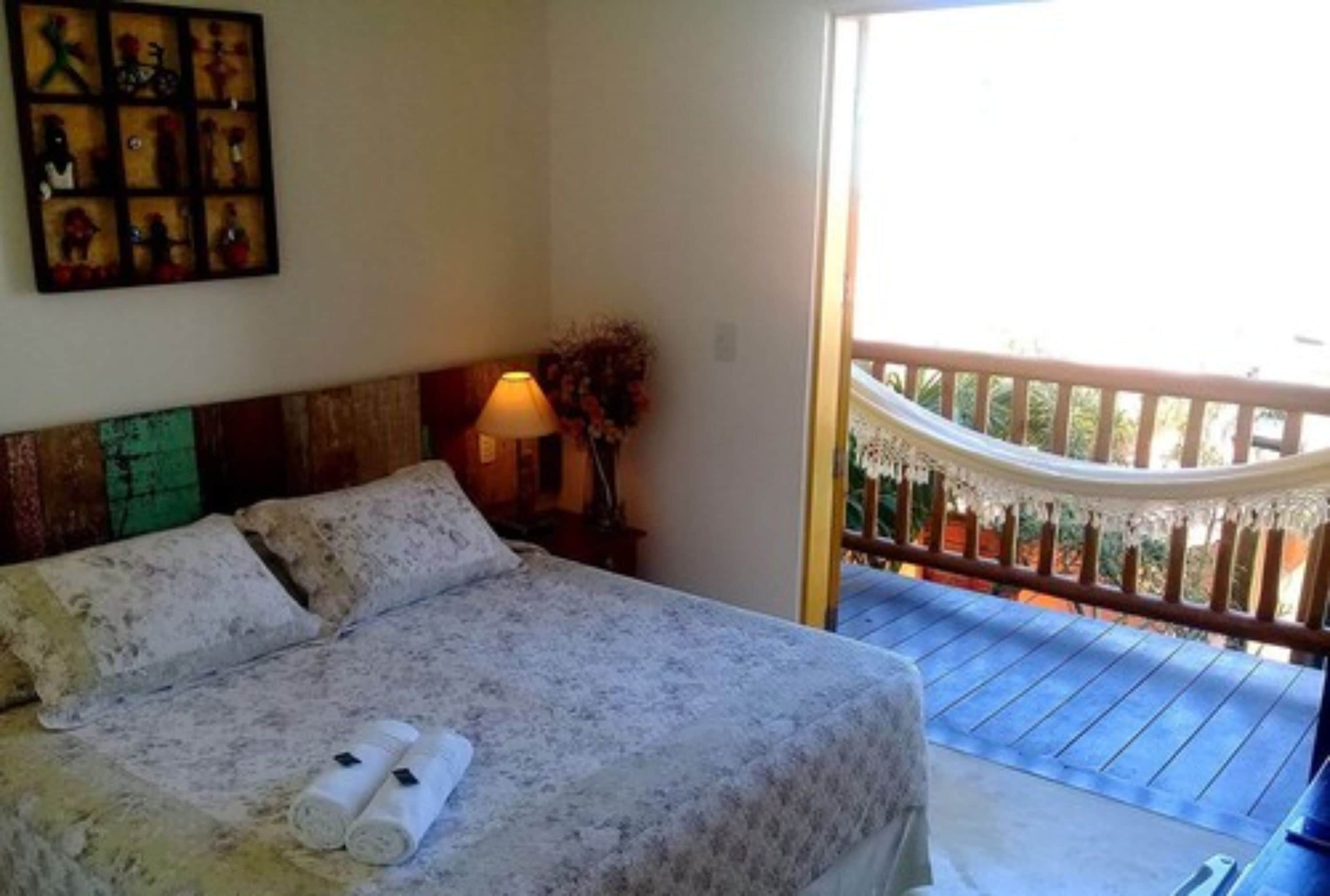 A bedroom with a bed, a nightstand, and a balcony with a railing.