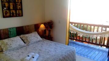 A bedroom with a bed, a nightstand, and a balcony with a railing.