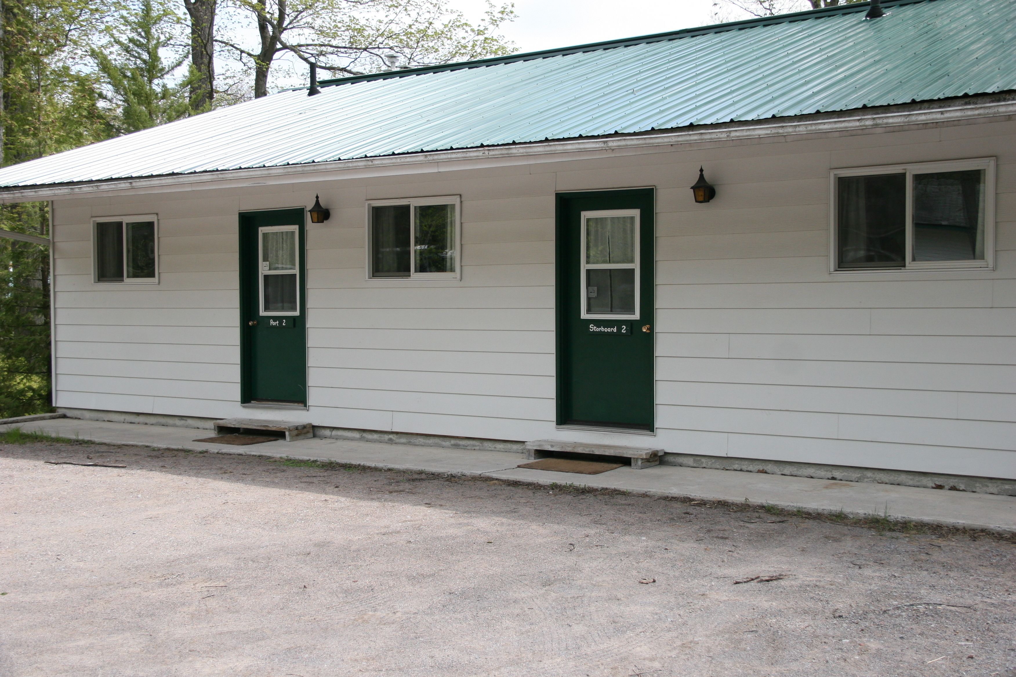 A row of two-room cabins with green doors and windows, each labeled "Room 2".