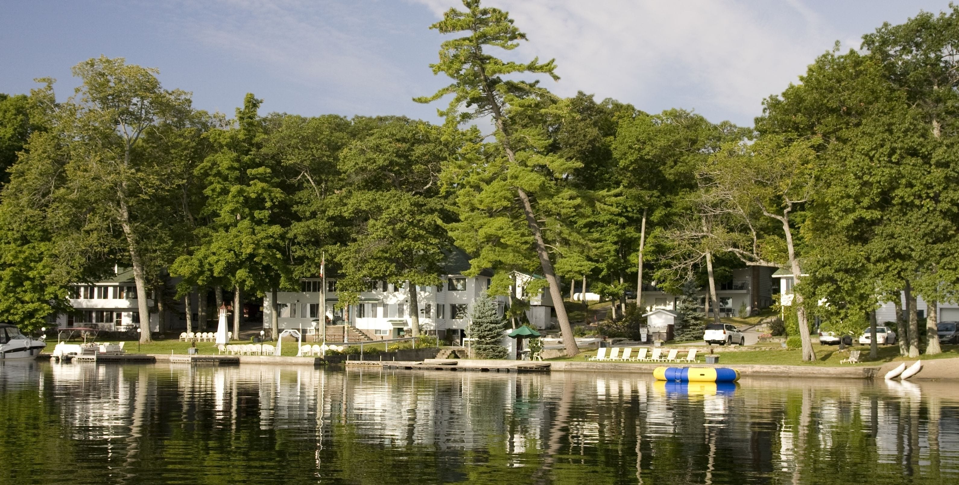 A lakeside view with boats, a dock, and a row of houses.