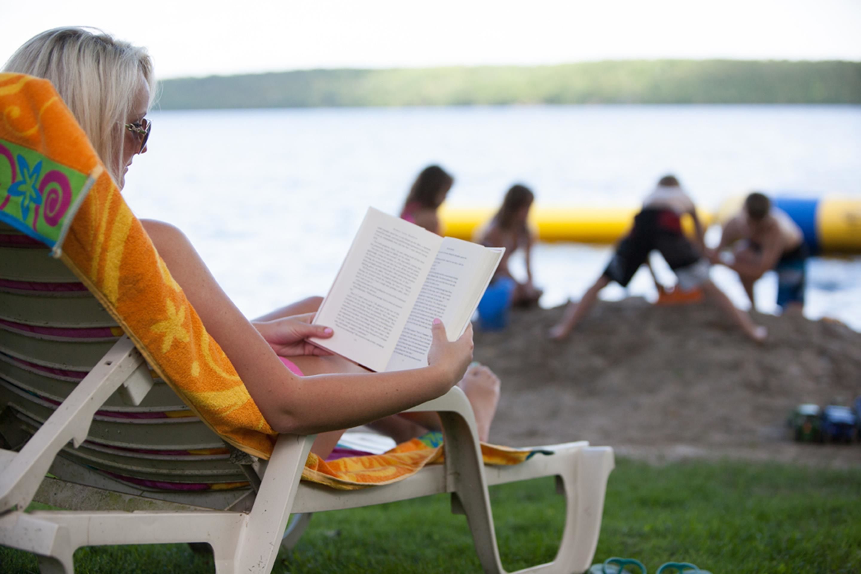 Una persona leyendo un libro en una silla de playa.