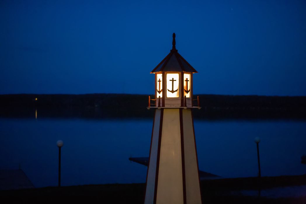 A lighthouse with a light at the top, situated near a body of water.