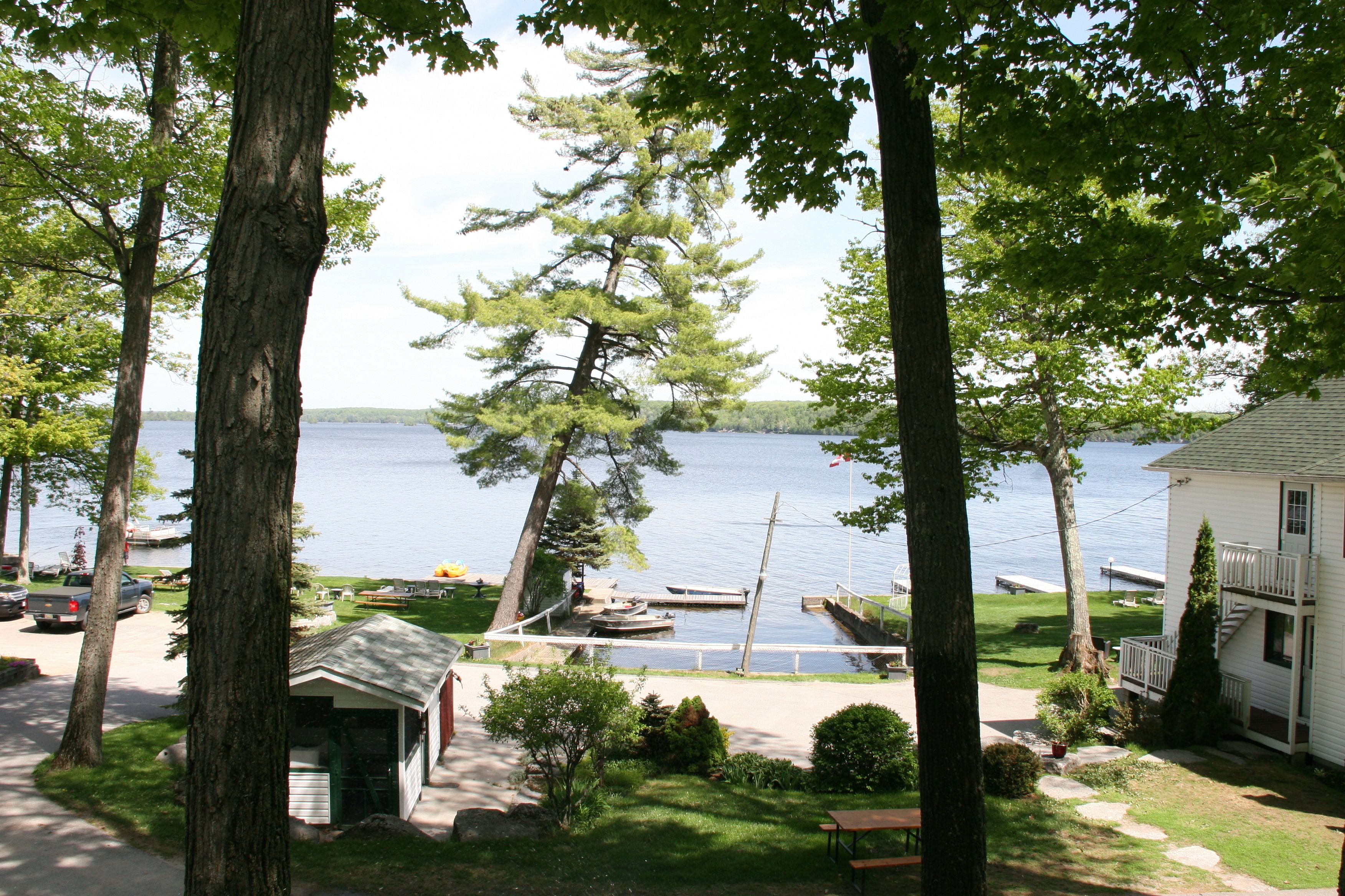 A lakeside property with a dock, a small shed, and a house with a balcony.