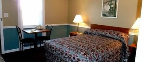 A hotel room with a bed, a desk, and a chair.