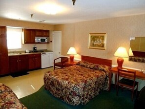 A hotel room with a bed, a desk, a chair, a microwave, and a small kitchenette. - Mamaroneck Motel (Mamaroneck)