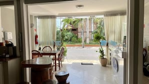 Un hall de hotel con zona de comedor, un extintor y un letrero que indica una salida de emergencia.
