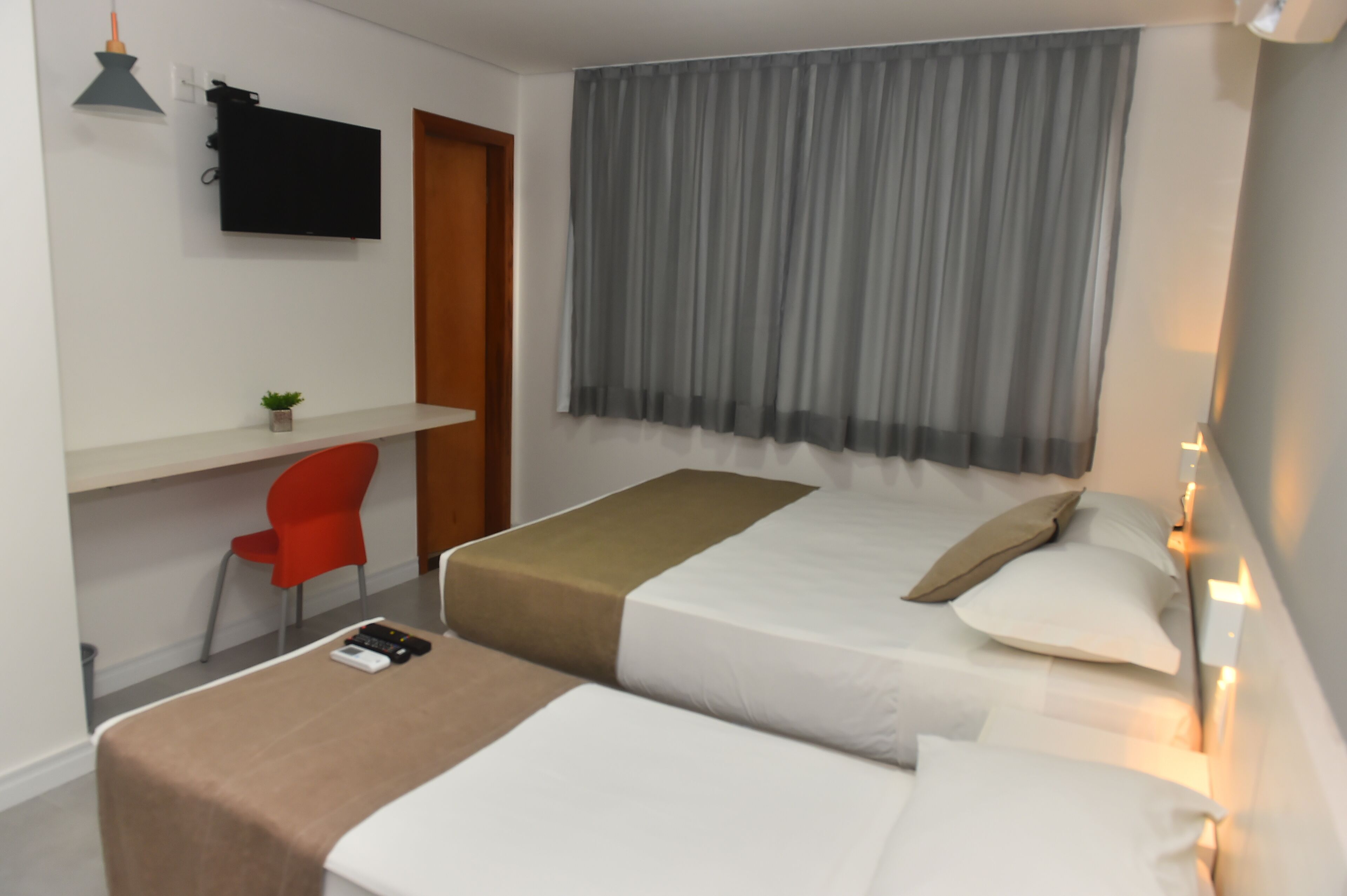 Une chambre d’hôtel avec un lit, une table de chevet, une télévision et une chaise.