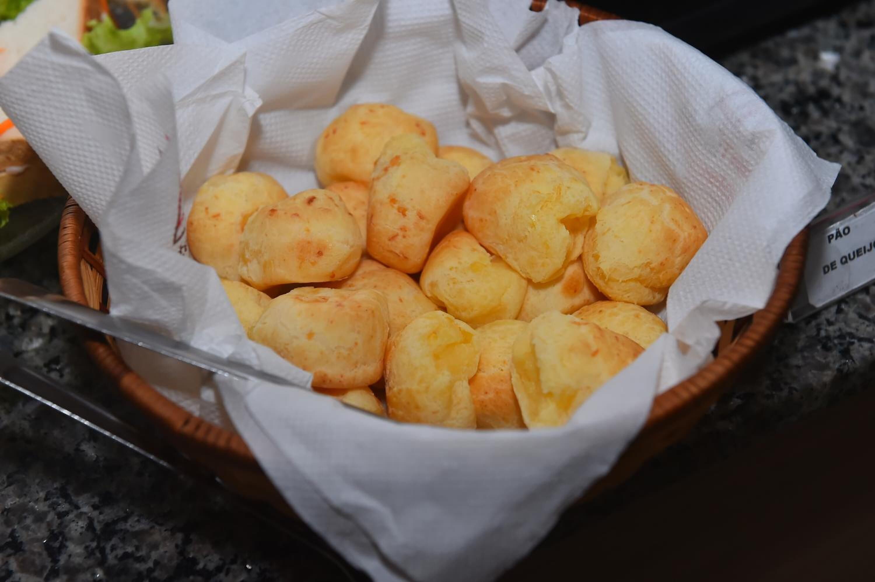 A basket of pão de queijo on a table.