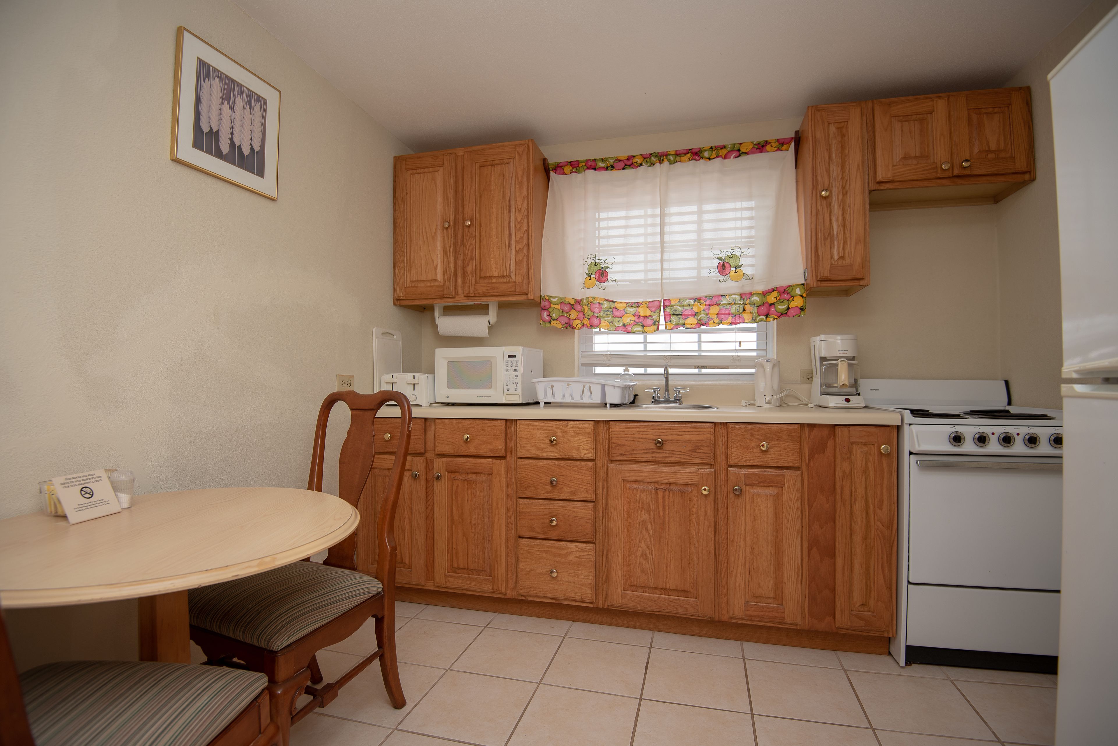 Une cuisine avec des meubles de rangement en bois, un four à micro-ondes, une cuisinière et une table à manger avec des chaises.