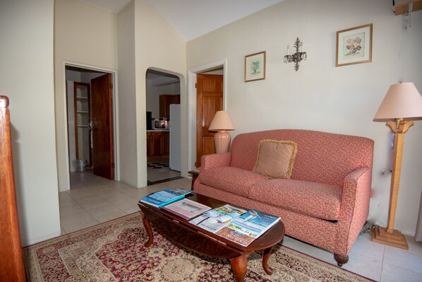 A living room with a red patterned sofa, a coffee table with magazines, and two floor lamps.