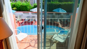 A sliding glass door leading to an outdoor pool area with chairs and a table. - Dawkins Manor Hotel (Paget Parish)