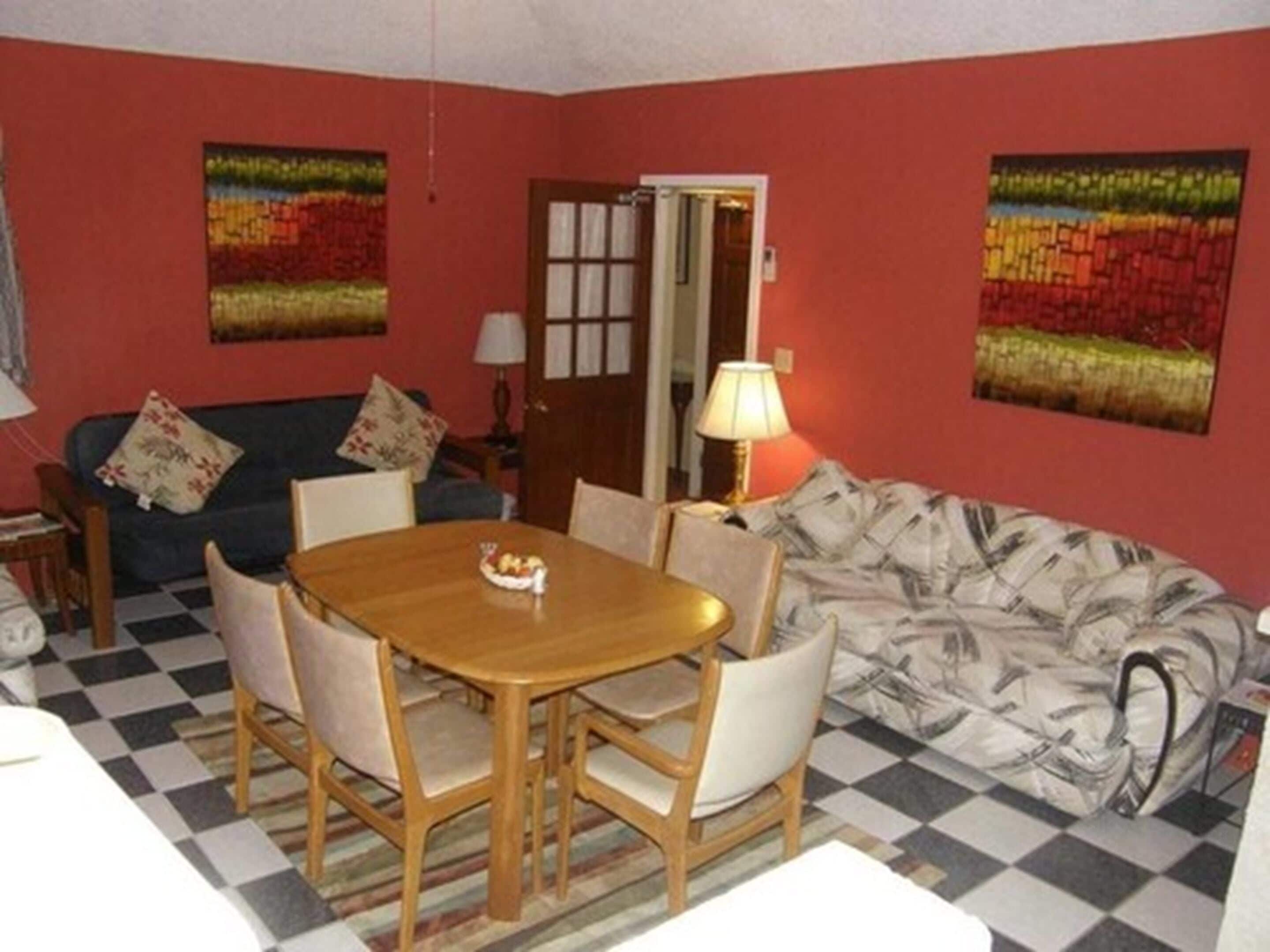Une pièce comprenant une table à manger, des chaises, un canapé et deux tableaux accrochés aux murs.