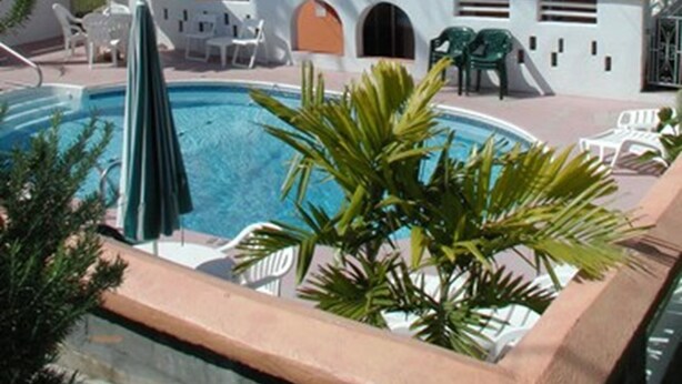 A hotel with a swimming pool, outdoor seating, and a covered area with umbrellas. - Dawkins Manor Hotel (Paget Parish)