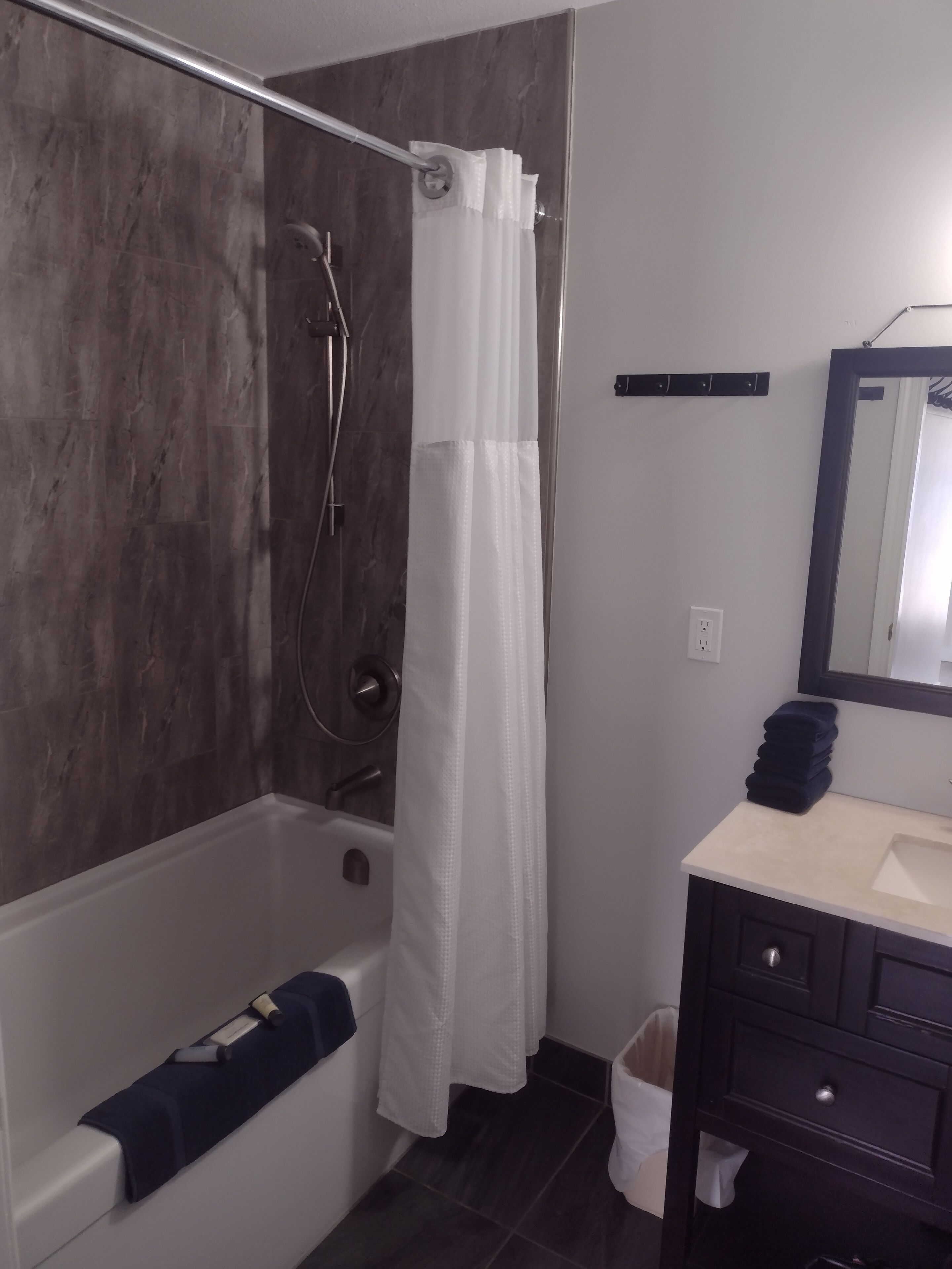 A modern bathroom with a bathtub, a shower, a sink, and a mirror.