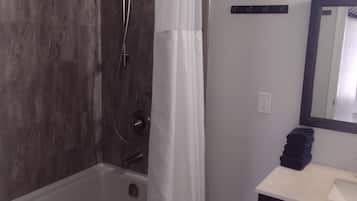 A modern bathroom with a bathtub, a shower, a sink, and a mirror.