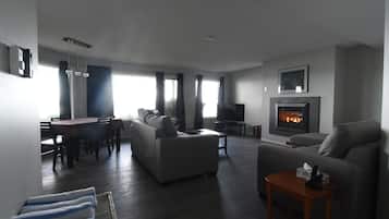 A modern living room with a fireplace, a dining area, and a sofa.