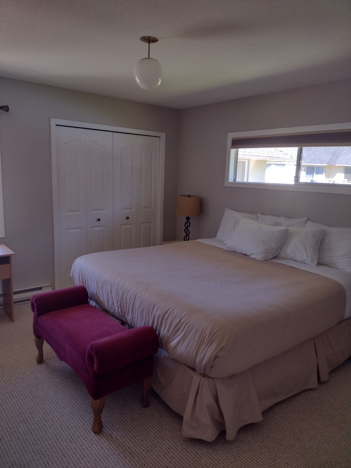 Un dormitorio con una cama grande, un escritorio, una silla, un armario y una ventana.