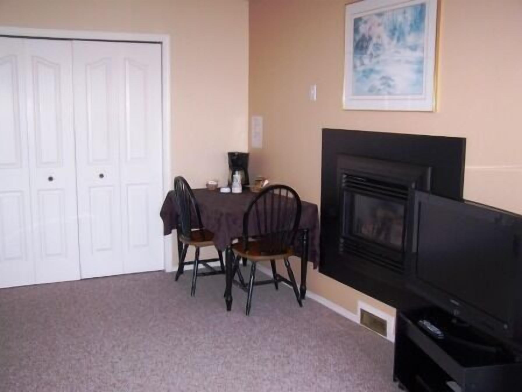 A room with a dining table, chairs, a fireplace, and a television.