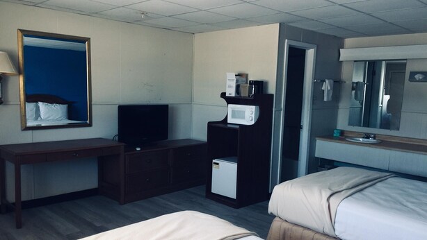 A hotel room with two beds, a desk with a television, a microwave, and a small refrigerator.