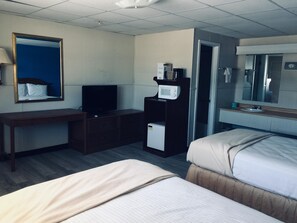Habitación de hotel con dos camas, un escritorio, televisión, microondas y refrigerador pequeño.
