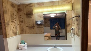 A bathroom with a wooden panel wall, a white sink, and a mirror.