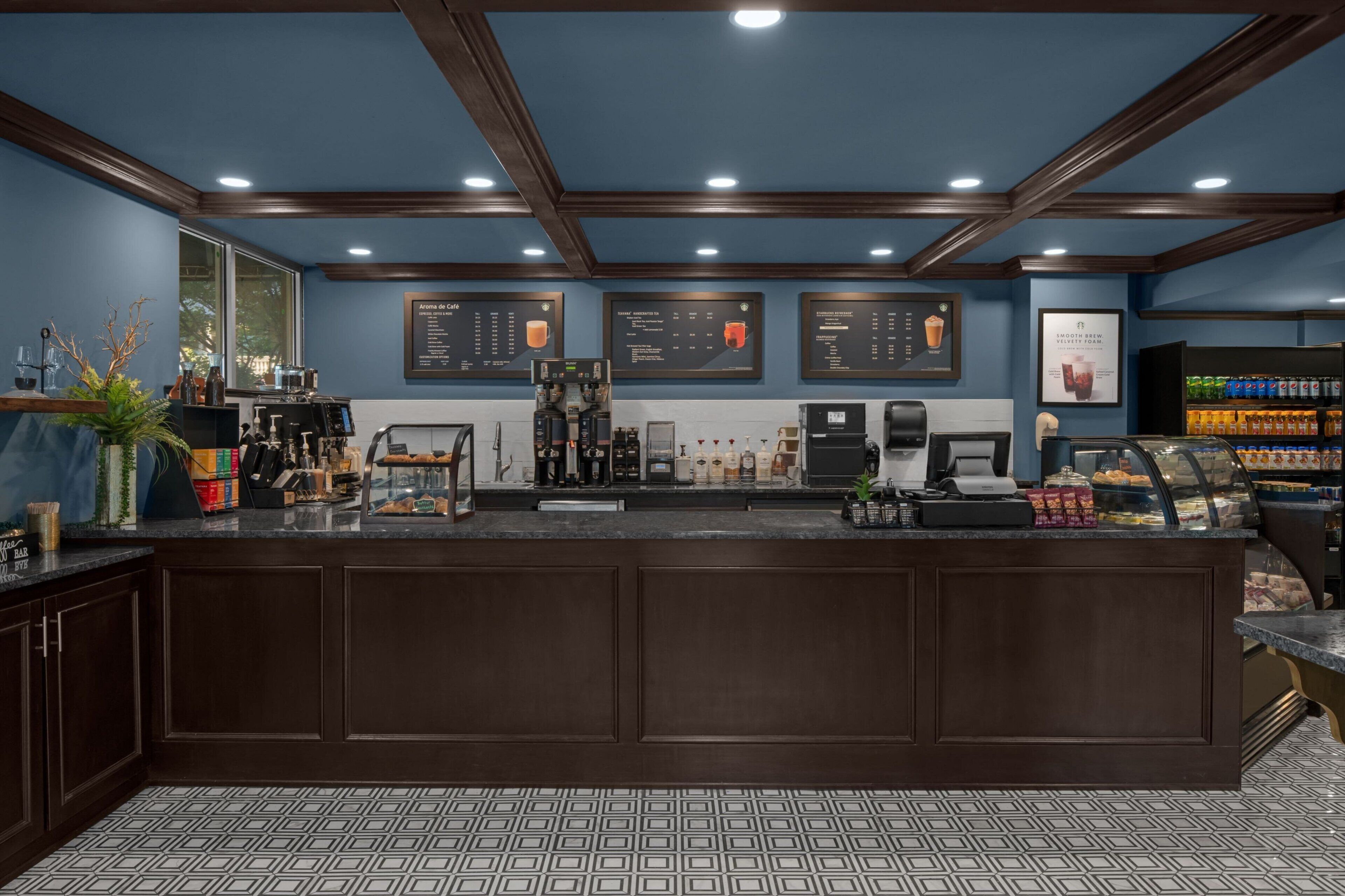 Ein Café-Interieur mit einer Theke, Espressomaschinen, Speisekarte und einer Getränkeauslage.