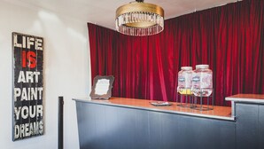 A reception desk with a red curtain backdrop, a chandelier, and a motivational sign on the wall. - LiA Hotel (San Carlos)