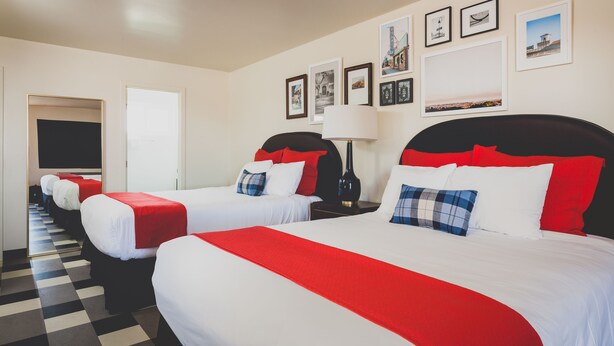 A hotel room with two beds, each with red and white bedding, a checkered floor, and framed pictures on the wall. - LiA Hotel (San Carlos)