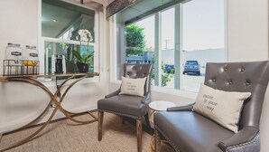 A room with two leather chairs, a small table with jars, and a window with a view of the street. - LiA Hotel (San Carlos)