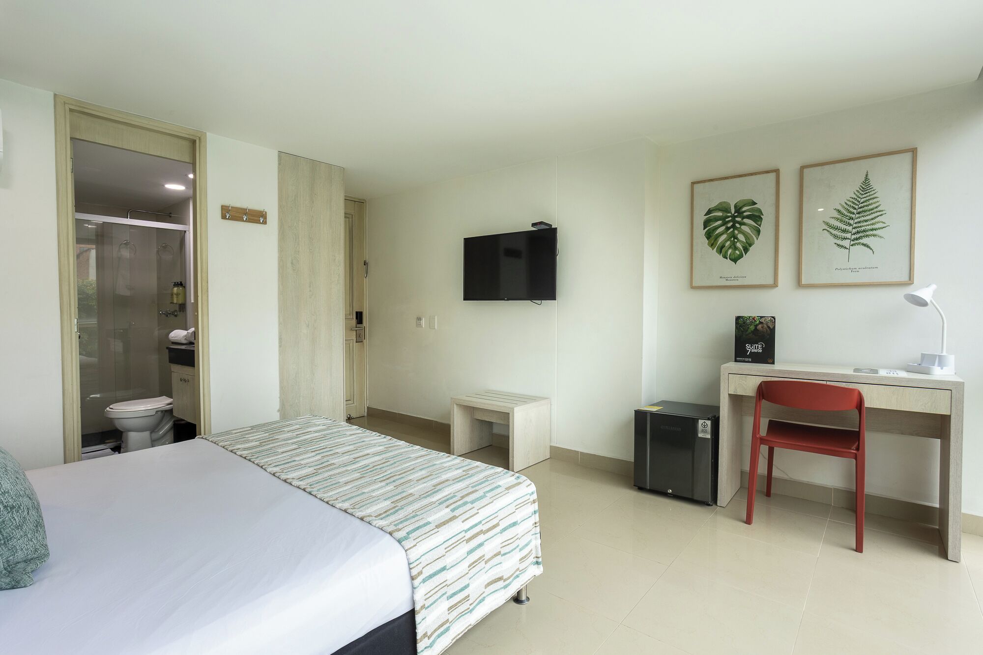 Une chambre d’hôtel comprenant un lit, un bureau, une chaise, une télévision et un petit placard.