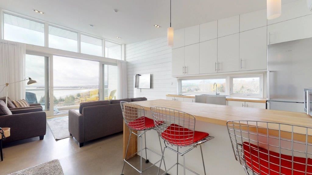 A modern kitchen with white cabinetry, a large island, and a view of the city.