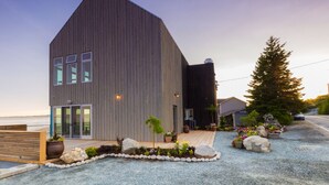 A modern two-story building with a sloped roof, large windows, and a wooden deck in front. - The Quarterdeck Resort (Summerville Centre)