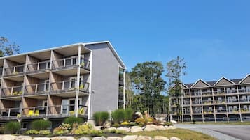 Ein mehrstöckiges Hotel mit Balkonen, ein angelegter Garten mit Steinen und Pflanzen und einem strahlend blauen Himmel.
