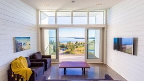 A modern living room with a large sliding glass door leading to a scenic outdoor view. - The Quarterdeck Resort (Summerville Centre)